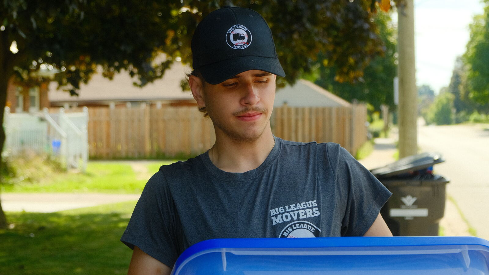 Big League Movers crew member carrying a moving bin