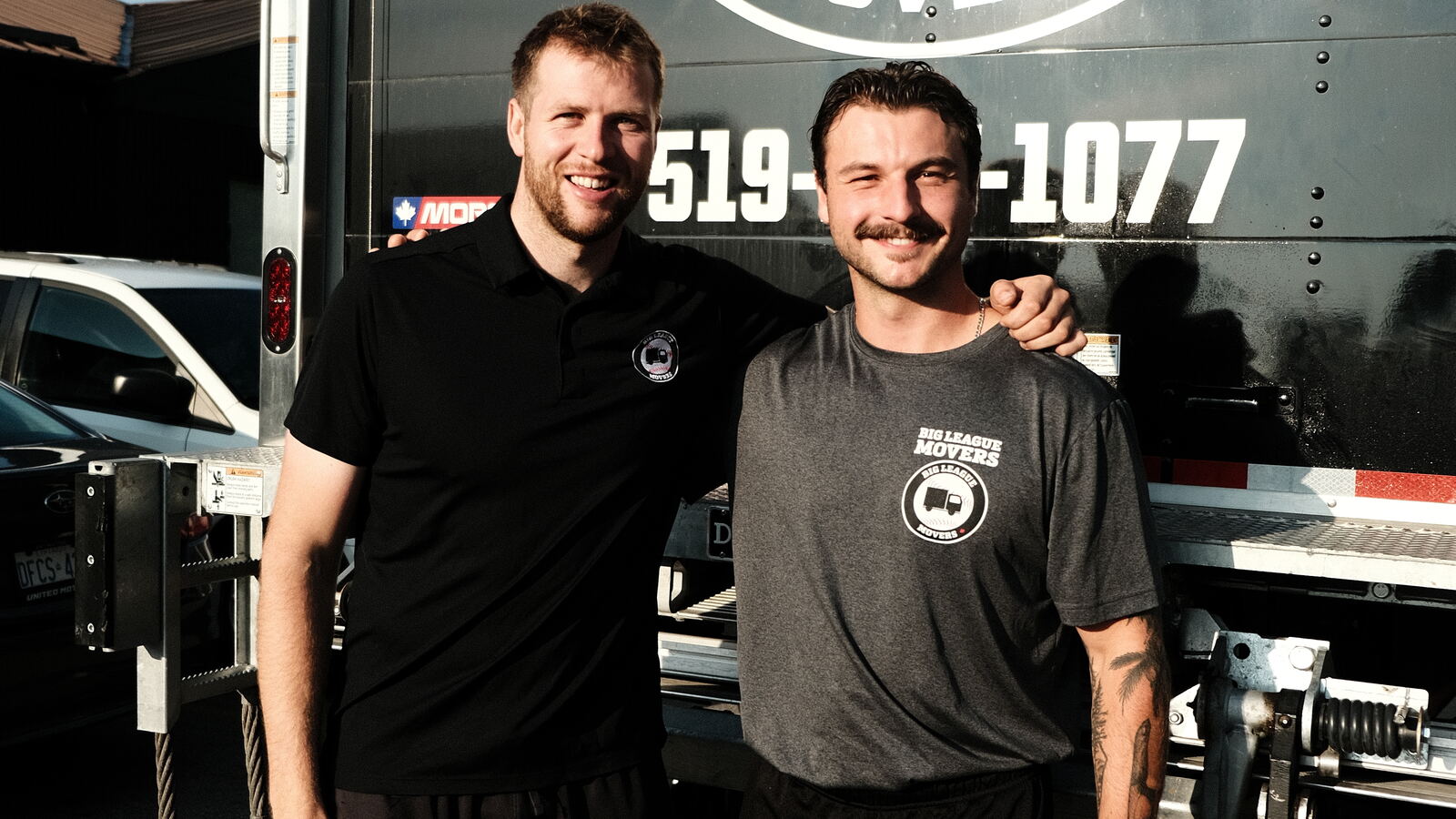 Two Big League Movers crew members in front of the truck