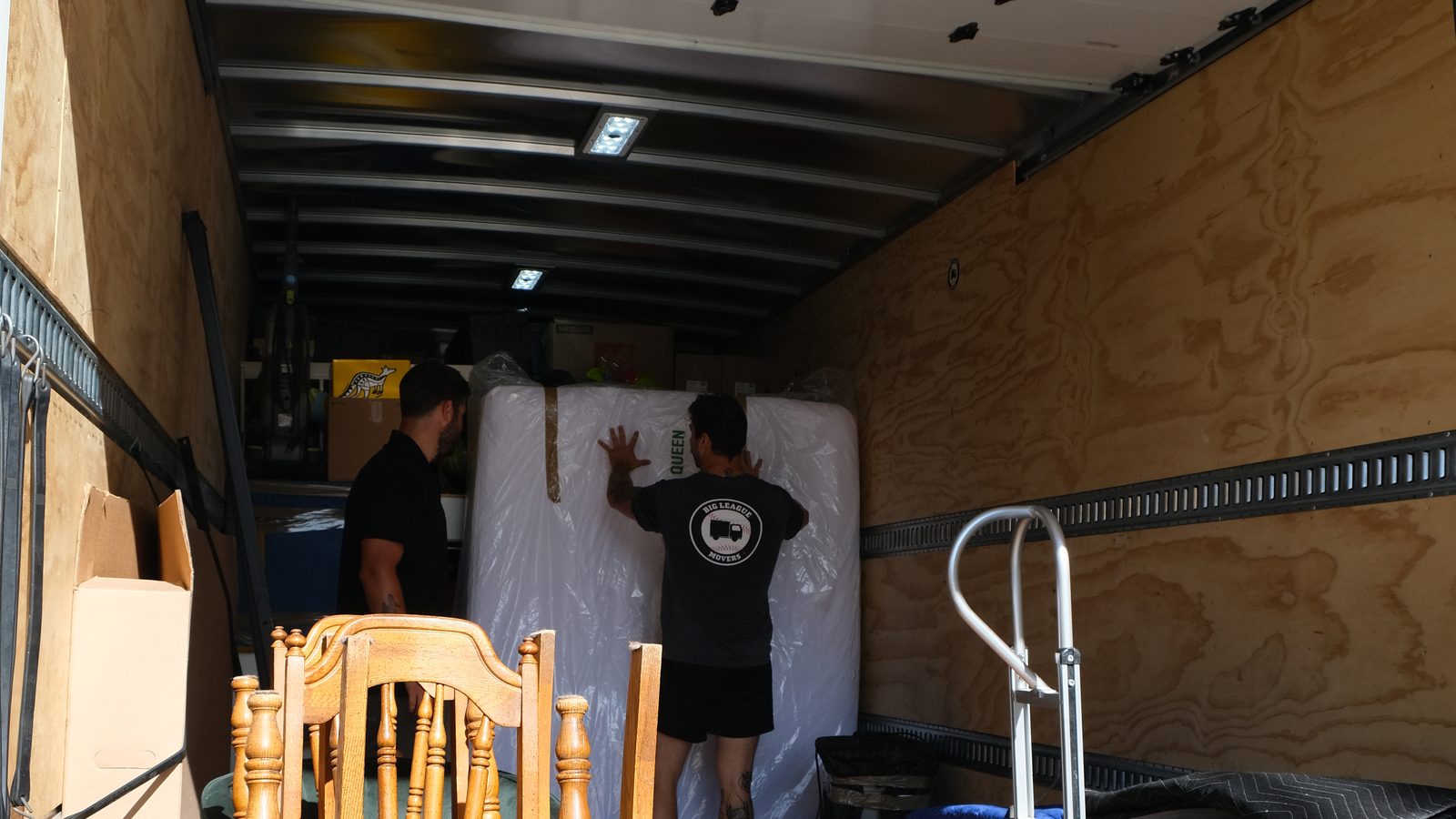 Big League Movers crew carefully loading furniture inside the truck