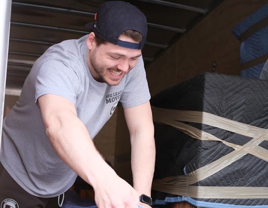 Big League Movers crew member carefully wrapping and strapping furniture